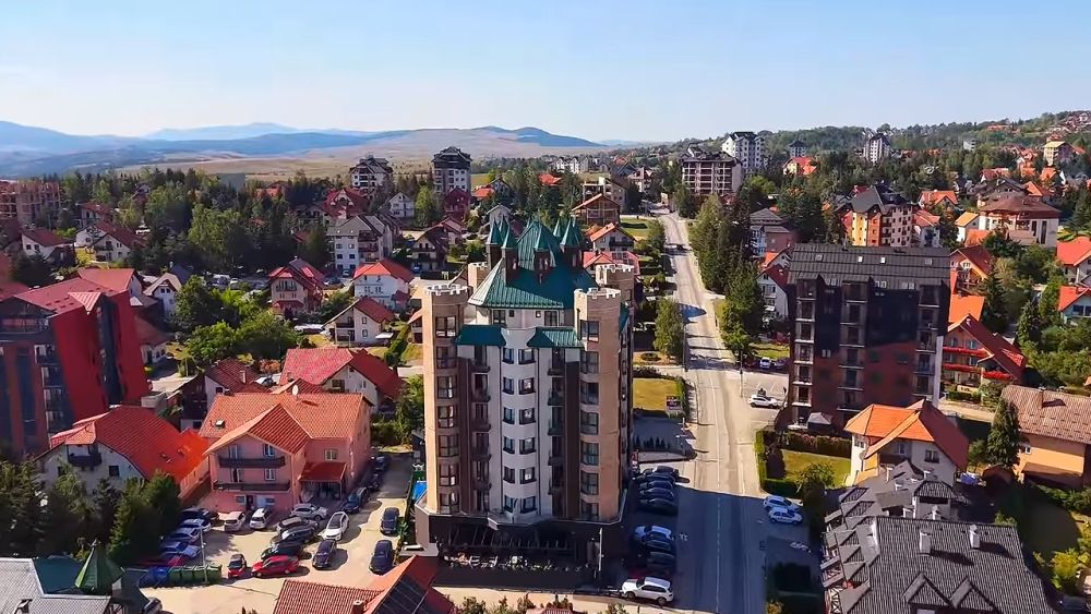 Pogled iz vazduha na zgrade, kuće, ulice i parkirane automobile u naseljenom delu Zlatibora.